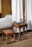 Table de style Louis XIII et tabouret à pieds en balustre devant un lit de la salle des hommes. © Région Bourgogne-Franche-Comté, Inventaire du patrimoine