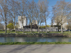 L'église Saint-Elisabeth vue du canal. Son toit apparaît derrière la rangée d'arbres d'alignement et le mur de limite de propriété. Derrière, le quartier de la Fontaine-d'Ouche. © Région Bourgogne-Franche-Comté, Inventaire du patrimoine