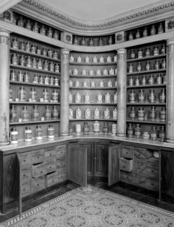 Bâtiment dit de l'administration : pharmacie, angle antérieur droit, vue d'ensemble avec portes des placards ouvertes et tiroirs à plantes médicinales. © Région Bourgogne-Franche-Comté, Inventaire du patrimoine