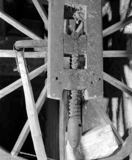 Vis de réglage en hauteur de l'axe de la roue et inscription. À l'arrière-plan, bielle, manivelle et poids équilibrant la roue. © Région Bourgogne-Franche-Comté, Inventaire du patrimoine