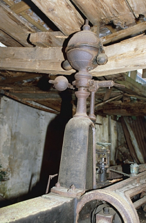 Machine à vapeur : détail du régulateur à boules. L'entrait de la charpente, brisé, repose sur le régulateur. © Région Bourgogne-Franche-Comté, Inventaire du patrimoine