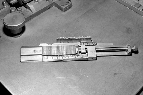 Face supérieure du composteur permettant le centrage des caractères sur la ligne. Le caractère apparaît au recto de chaque matrice ; la ligne-bloc fondue est placée à côté du composteur. © Région Bourgogne-Franche-Comté, Inventaire du patrimoine