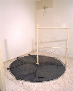 Sous-sol, salle ouest : puits des pendules à pression constante, trappe fermée. © Région Bourgogne-Franche-Comté, Inventaire du patrimoine Sous-sol, salle ouest : puits des pendules à pression constante, trappe fermée. © Région Bourgogne-Franche-Comté, Inventaire du patrimoine