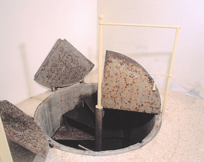 Sous-sol, salle ouest : puits des pendules à pression constante, trappe ouverte. © Région Bourgogne-Franche-Comté, Inventaire du patrimoine Sous-sol, salle ouest : puits des pendules à pression constante, trappe ouverte. © Région Bourgogne-Franche-Comté, Inventaire du patrimoine