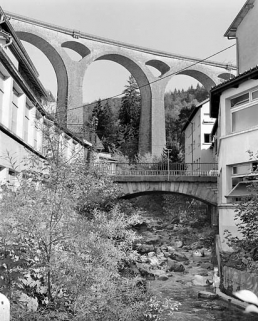 Pont de l'Evalude : vue d'ensemble, depuis la rive droite en aval. En arrière-plan, le grand viaduc de Séjourné portant la voie ferrée Morez - Saint-Claude (tronçon de la ligne Andelot - La Cluse). © Région Bourgogne-Franche-Comté, Inventaire du patrimoine Pont de l'Evalude : vue d'ensemble, depuis la rive droite en aval. En arrière-plan, le grand viaduc de Séjourné portant la voie ferrée Morez - Saint-Claude (tronçon de la ligne Andelot - La Cluse). © Région Bourgogne-Franche-Comté, Inventaire du patrimoine