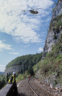 Sécurisation de paroi rocheuse à Syam : hélicoptère et rouleau de filet de protection en cours de levage. © Région Bourgogne-Franche-Comté, Inventaire du patrimoine Sécurisation de paroi rocheuse à Syam : hélicoptère et rouleau de filet de protection en cours de levage. © Région Bourgogne-Franche-Comté, Inventaire du patrimoine
