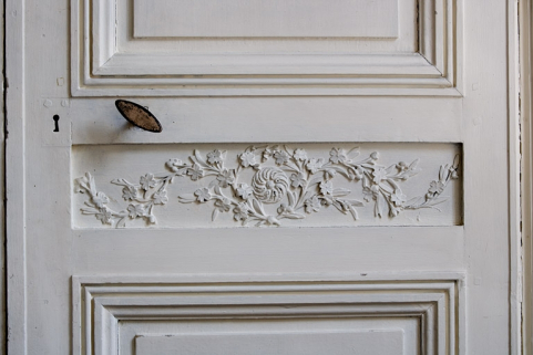 Intérieur, premier étage : détail du décor sculpté d'un panneau médian de la porte d'entrée de la bibliothèque. © Région Bourgogne-Franche-Comté, Inventaire du Patrimoine