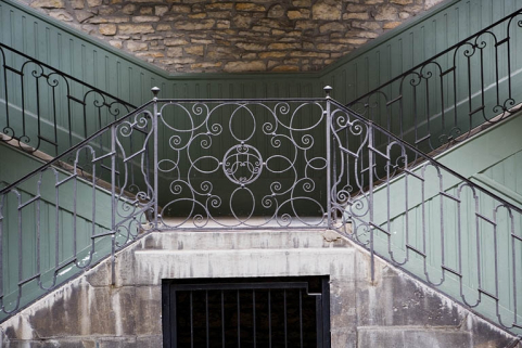 Escalier à cage ouverte à droite de la première cour : détail de la grille en ferronnerie. © Région Bourgogne-Franche-Comté, Inventaire du patrimoine