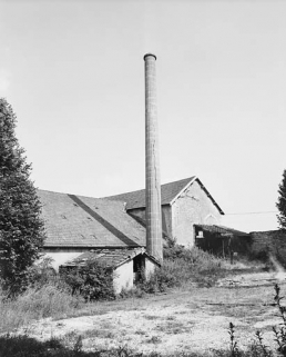 La cheminée et l'atelier de fabrication depuis le nord-ouest en 1981. © Région Bourgogne-Franche-Comté, Inventaire du patrimoine La cheminée et l'atelier de fabrication depuis le nord-ouest en 1981. © Région Bourgogne-Franche-Comté, Inventaire du patrimoine