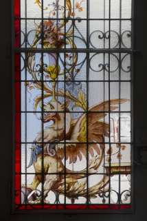 Intérieur, vitrail dans une fenêtre du rez-de-chaussée : détail du motif droit représentant un dragon ailé. © Région Bourgogne-Franche-Comté, Inventaire du Patrimoine