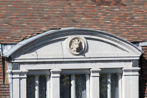 Façade sur rue : détail du fronton cintré de la baie centrale du comble décoré d'une tête de lion. © Région Bourgogne-Franche-Comté, Inventaire du Patrimoine