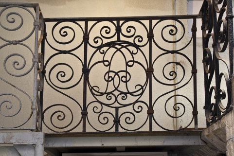 Première cour, escalier à cage ouverte : détail d'un panneau de la rampe en fer forgé avec un monogramme. © Région Bourgogne-Franche-Comté, Inventaire du Patrimoine