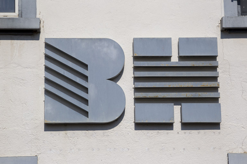 Usine, 1er corps de bâtiment : logotype de la société Bernard Haenni, sur la façade latérale gauche. © Région Bourgogne-Franche-Comté, Inventaire du patrimoine Usine, 1er corps de bâtiment : logotype de la société Bernard Haenni, sur la façade latérale gauche. © Région Bourgogne-Franche-Comté, Inventaire du patrimoine