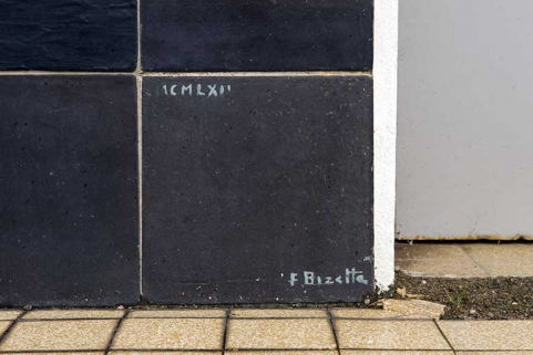 Oeuvre de Bizette. Signature et date du panneau gauche flanquant l'entrée. © Région Bourgogne-Franche-Comté, Inventaire du patrimoine