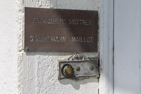 Façade latérale gauche : plaque de la fabrique de montres Stadelmann-Maillot, à l'entrée. © Région Bourgogne-Franche-Comté, Inventaire du patrimoine