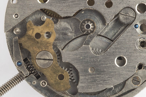 1er mouvement, côté cadran : détail du mécanisme du remontoir. A gauche, tige de remontoir et son pignon, et plaque protégeant les renvois. © Région Bourgogne-Franche-Comté, Inventaire du patrimoine