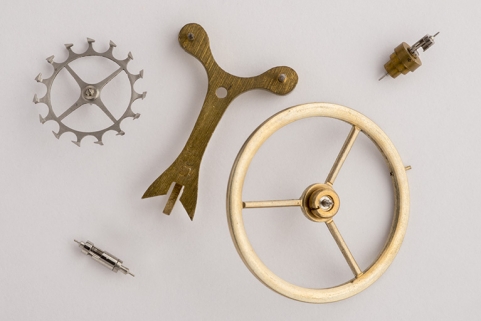 Ensemble de fournitures pour échappement de montre et de réveil. Par ordre de dimension décroissante : un balancier, une ancre à chevilles, une roue de cylindre et deux cylindres. © Région Bourgogne-Franche-Comté, Inventaire du patrimoine