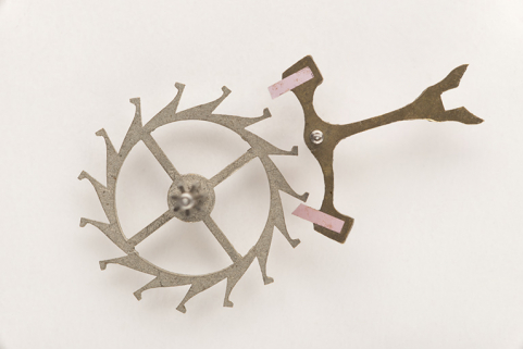 L'organe de partage et distribution du temps de la montre : l'échappement à ancre (roue d'ancre à gauche, ancre - avec palettes en rubis synthétique - à droite). © Région Bourgogne-Franche-Comté, Inventaire du patrimoine L'organe de partage et distribution du temps de la montre : l'échappement à ancre (roue d'ancre à gauche, ancre - avec palettes en rubis synthétique - à droite). © Région Bourgogne-Franche-Comté, Inventaire du patrimoine