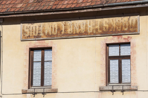 Façade antérieure : encadrements de fenêtres peints en trompe-l'oeil et enseigne réutilisée. © Région Bourgogne-Franche-Comté, Inventaire du patrimoine