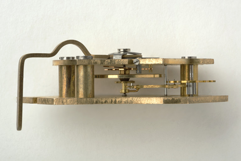 Vue de profil. A gauche queue de raquette ; au centre de haut en bas : raquette, ressort spiral et sa fixation, balancier, plateau avec son ellipse et fourchette de l'ancre ; à droite ancre fixée sur son axe puis roue d'ancre avec son pignon. © Région Bourgogne-Franche-Comté, Inventaire du patrimoine