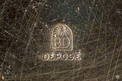 Poinçon d'origine étrangère (lettres B et D sous un soleil), gravé dans le fond. © Région Bourgogne-Franche-Comté, Inventaire du patrimoine