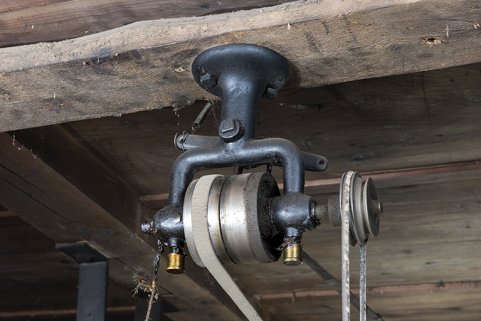 Renvoi de mouvement à deux graisseurs. La fourchette, commandée par la corde à gauche, se devine à l'arrière-plan. © Région Bourgogne-Franche-Comté, Inventaire du patrimoine