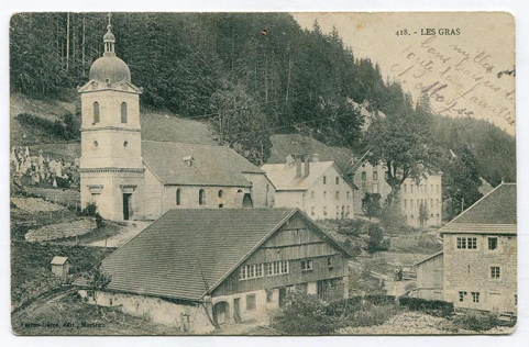 418. - Les Gras [le quartier de l'église vu du sud], 1er quart 20e siècle [avant 1916]. Le bâtiment est visible à droite (l'atelier se signale par la fenêtre horlogère au dernier niveau). © Région Bourgogne-Franche-Comté, Inventaire du patrimoine