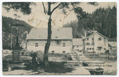 Le Doubs pittoresque. 108 - Les Gras - Le calvaire et l'entrée du village, 1er quart 20e siècle [avant 1916]. Façade latérale droite de la maison avant transformation. © Région Bourgogne-Franche-Comté, Inventaire du patrimoine