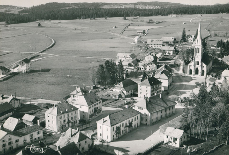 Le Russey (Doubs) - Alt. 900 m. 37730 A - Vue panoramique aérienne [le village vu du sud], 3e quart 20e siècle. Le bâtiment est visible à gauche. © Région Bourgogne-Franche-Comté, Inventaire du patrimoine