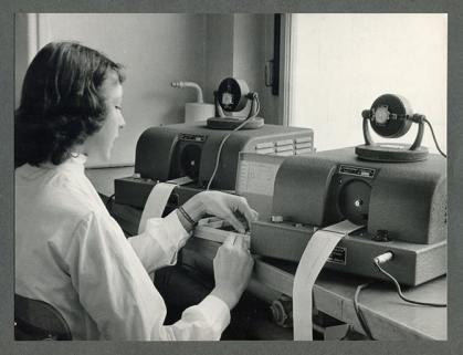 Ouvrière au travail : contrôle de marche au chronocomparateur (Vibrograf Lepaute), années 1960. © Région Bourgogne-Franche-Comté, Inventaire du patrimoine Ouvrière au travail : contrôle de marche au chronocomparateur (Vibrograf Lepaute), années 1960. © Région Bourgogne-Franche-Comté, Inventaire du patrimoine