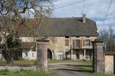 Les piliers du portail d'entrée et la maison en arrière-plan. © Région Bourgogne-Franche-Comté, Inventaire du patrimoine