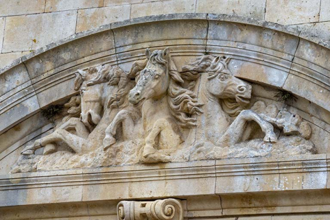 Fronton cintré orné d'un haut-relief représentant trois chevaux, vue de trois-quarts. © Région Bourgogne-Franche-Comté, Inventaire du patrimoine Fronton cintré orné d'un haut-relief représentant trois chevaux, vue de trois-quarts. © Région Bourgogne-Franche-Comté, Inventaire du patrimoine