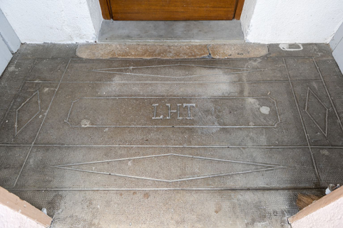 Bâtiment au 2 rue du Chêne : initiales de Lucien Hugoniot-Tissot sur le sol de l'entrée. © Région Bourgogne-Franche-Comté, Inventaire du patrimoine Bâtiment au 2 rue du Chêne : initiales de Lucien Hugoniot-Tissot sur le sol de l'entrée. © Région Bourgogne-Franche-Comté, Inventaire du patrimoine