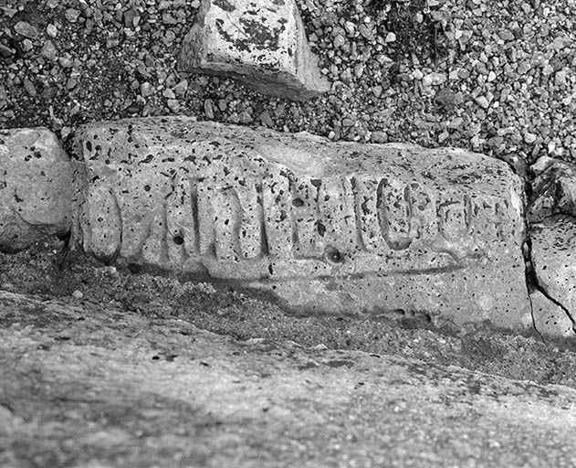 Elévation gauche : fragment de dalle funéraire remployé à la base d'un contrefort. © Région Bourgogne-Franche-Comté, Inventaire du patrimoine