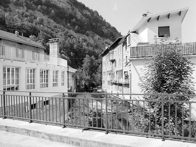 Anciennes usines de lunetterie Poux puis Chevassus (90 rue de la République) et Vinsard puis Petit-Prost (au n° 84). La Bienne coule entre l'usine Poux (à gauche) et l'usine Vinsard (à droite au fond), qui se signale par ses fenêtres multiples et se… © Région Bourgogne-Franche-Comté, Inventaire du patrimoine Anciennes usines de lunetterie Poux puis Chevassus (90 rue de la République) et Vinsard puis Petit-Prost (au n° 84). La Bienne coule entre l'usine Poux (à gauche) et l'usine Vinsard (à droite au fond), qui se signale par ses fenêtres multiples et se… © Région Bourgogne-Franche-Comté, Inventaire du patrimoine