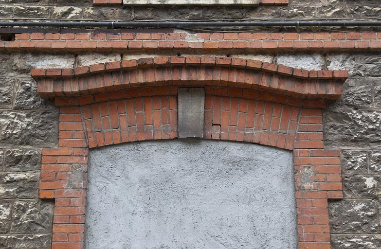 Atelier en pierre au n° 14B : arc en briques couvrant une porte murée de la façade latérale droite. © Région Bourgogne-Franche-Comté, Inventaire du patrimoine