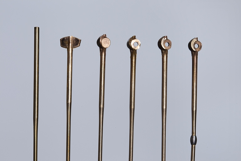 De gauche à droite, fil de bronze après refoulage et talonnage, perçage de l'oeil, mise à la largeur du chapeau, fraisage de l'oeil et du talon, sertissage de l'enjoliveur. © Région Bourgogne-Franche-Comté, Inventaire du patrimoine