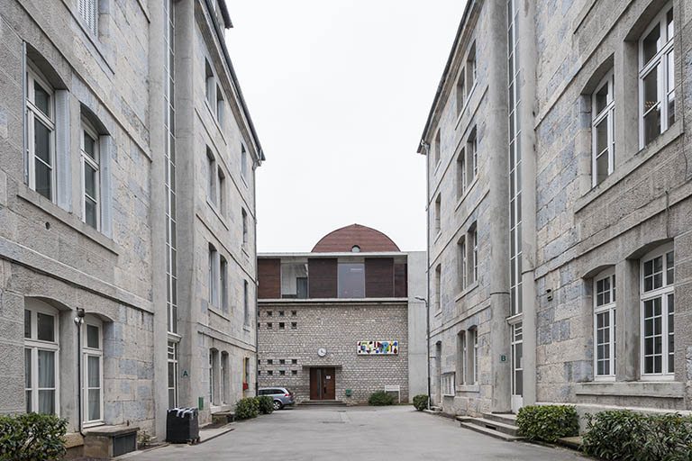 Depuis l'entrée du lycée, vue sur le pignon nord de l'externat, entre les deux pavillons des officiers. © Région Bourgogne-Franche-Comté, Inventaire du patrimoine