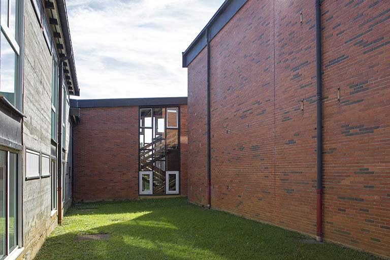 Cour délimitée par la façade ouest en béton de l'internat et la façade est en brique du gymnase. © Région Bourgogne-Franche-Comté, Inventaire du patrimoine
