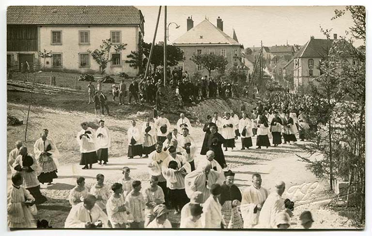 [Procession pour l'inauguration de la chapelle Sainte-Thérèse, rue de la Vierge (au niveau de la statue de Notre-Dame de Lourdes), le 3 juin 1929]. L'usine se devine à droite. © Région Bourgogne-Franche-Comté, Inventaire du patrimoine