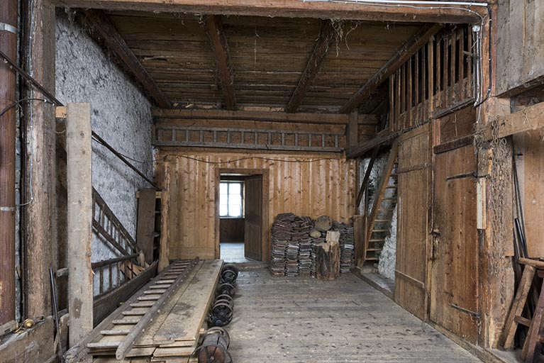 La grange, depuis l'entrée au nord. L'accès à l'atelier s'effectue par l'escalier en bois à droite. © Région Bourgogne-Franche-Comté, Inventaire du patrimoine
