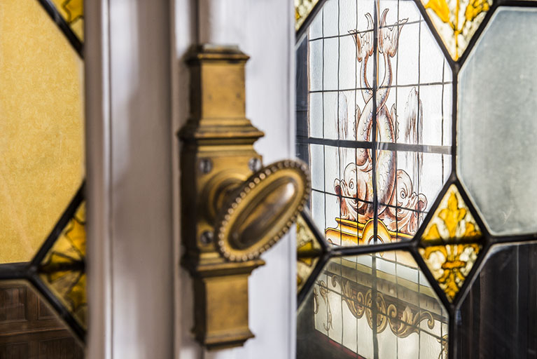 Aperçu de la verrière de la salle de bal par le châssis vitré à motifs géomètriques. © Région Bourgogne-Franche-Comté, Inventaire du patrimoine