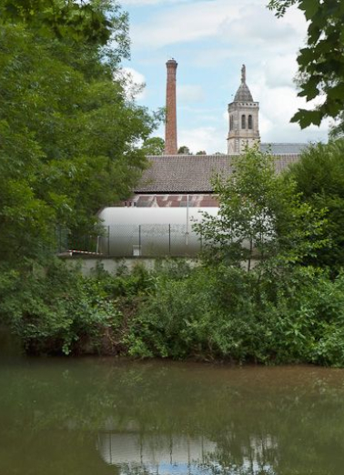 Vue de l'usine depuis le canal. On remarque la cheminée en briques rouges. © Région Bourgogne-Franche-Comté, Inventaire du patrimoine