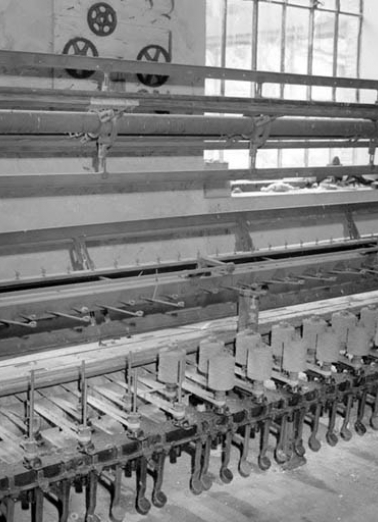 Détail du module de gauche, vu de trois quarts.De bas en haut, système de freinage des broches au pied, broches et leur courrois d'entrainement, système de guidage des fils et moulins. © Région Bourgogne-Franche-Comté, Inventaire du patrimoine