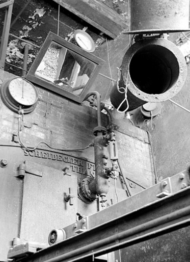 Détail de la partie haute de la chaudière de 1927 (cadrage vertical). Tuyau articulé de chargement de la trémie à droite ; rail et chariot de la trémie en bas. © Région Bourgogne-Franche-Comté, Inventaire du patrimoine