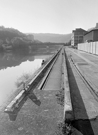Port fluvial : quai et vestiges de la voie de roulement de la grue mobile, depuis l'aval. © Région Bourgogne-Franche-Comté, Inventaire du patrimoine Port fluvial : quai et vestiges de la voie de roulement de la grue mobile, depuis l'aval. © Région Bourgogne-Franche-Comté, Inventaire du patrimoine