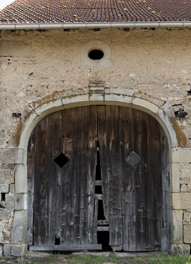 Alignement en bas du village, au nord de la fontaine. Détail de la porte charretière en anse de panier et de l'oculus ovale oblong.  © Région Bourgogne-Franche-Comté, Inventaire du patrimoine Alignement en bas du village, au nord de la fontaine. Détail de la porte charretière en anse de panier et de l'oculus ovale oblong.  © Région Bourgogne-Franche-Comté, Inventaire du patrimoine