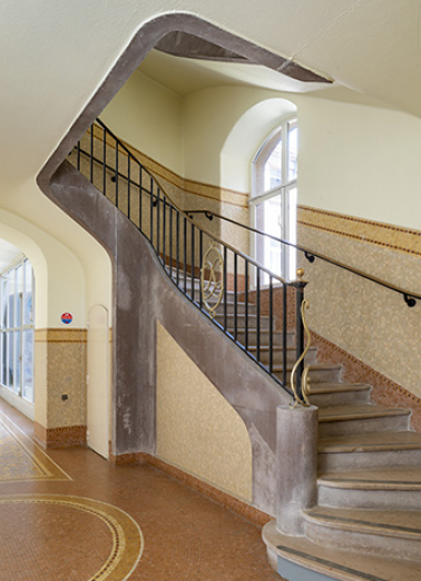Escalier à garde-corps métallique orné d'un médaillon ovale au chiffre de Luxeuil. © Région Bourgogne-Franche-Comté, Inventaire du patrimoine Escalier à garde-corps métallique orné d'un médaillon ovale au chiffre de Luxeuil. © Région Bourgogne-Franche-Comté, Inventaire du patrimoine