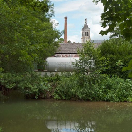 Vue de l'usine depuis le canal. On remarque la cheminée en briques rouges. © Région Bourgogne-Franche-Comté, Inventaire du patrimoine