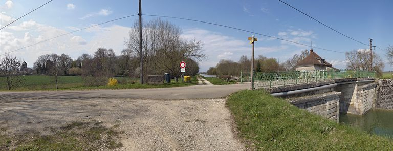 Ouges, Vue d'ensemble, de gauche à droite : église Saint-Pierre ; château avec parc situé rive droite du canal, en amont du pont sur écluse ; chemin de halage, pont sur écluse. On aperçoit derrière ce pont la maison éclusière. © Thierry Kuntz / Région Bourgogne-Franche-Comté, Inventaire du patrimoine - 2011